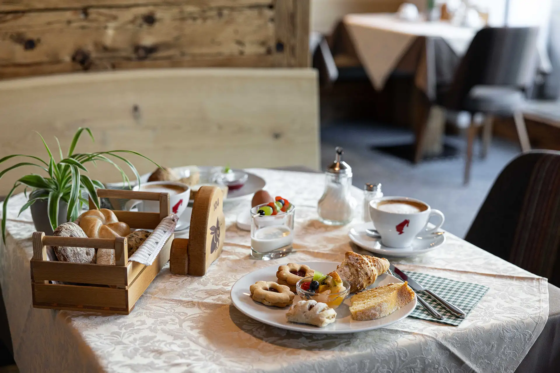 Holztisch mit lokalen Frühstücksprodukten im Farmhouse Plang in den Dolomiten.